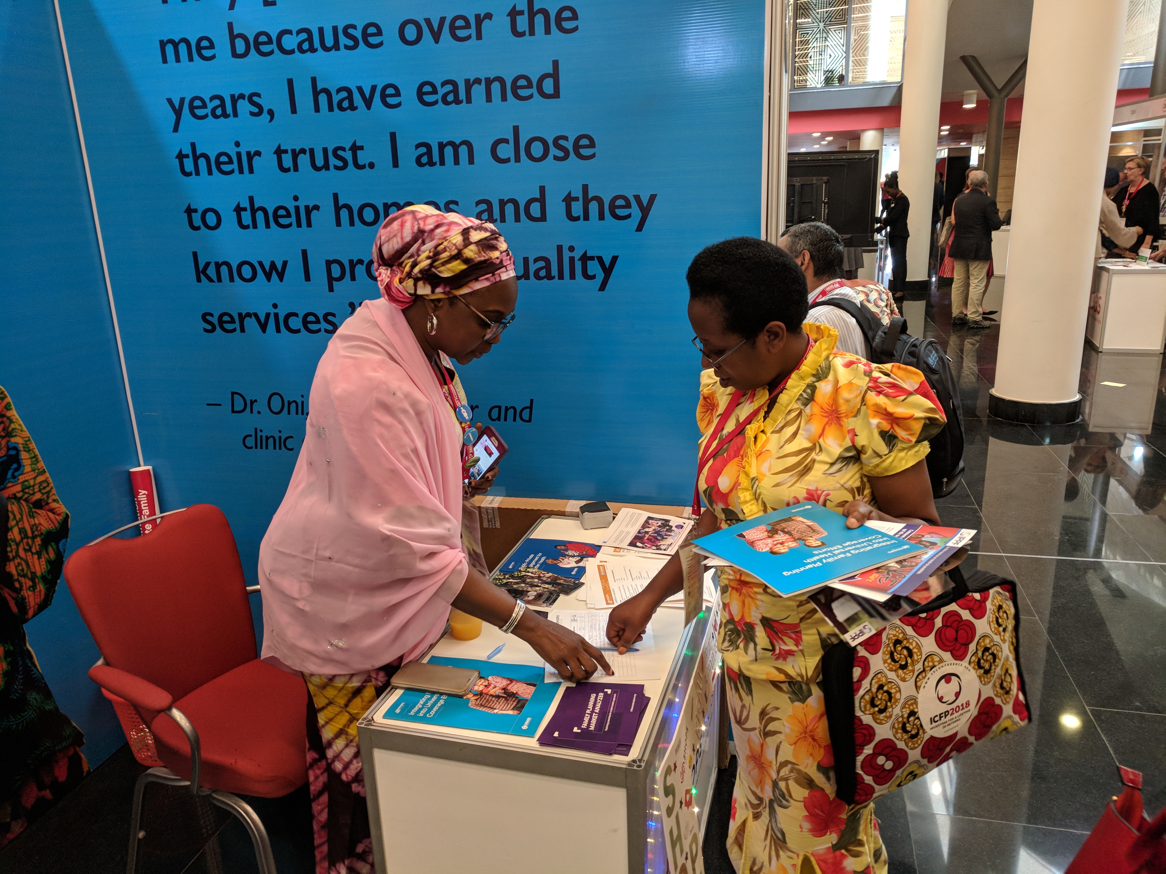 Amina talking to a visitor at the booth